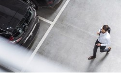 A photograph of a man walking in a car park