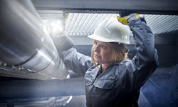 A photograph of a lady wearing a hard hat shining a torch