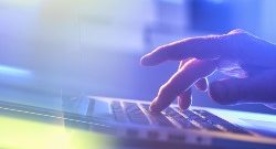 A photograph of a hand pressing the keypad on a laptop