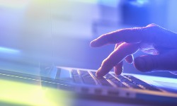 A photograph of a hand pressing the keypad on a laptop