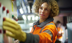 A photograph of a lady wearing a high visibility jacket & yellow gloves