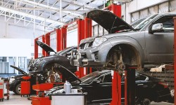 A photograph of cars lifted up to be worked on in a mechanics yard