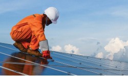 A photograph of a man installing solar panels