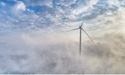 A photograph of a wind turbine in the clouds